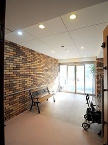 レンガ調の壁が印象的。玄関に段差はなくベンチやシルバーカーがある。