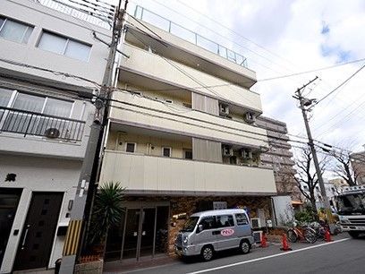 各フロアにベランダがついた白い４階建ての建物。周辺には自然が残りっている。
