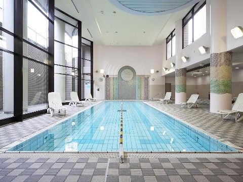 プールの中央にはコースロープが取り付けられている。白とグレーのタイルを格子状に張ったプールサイドには、白い椅子が置かれている。