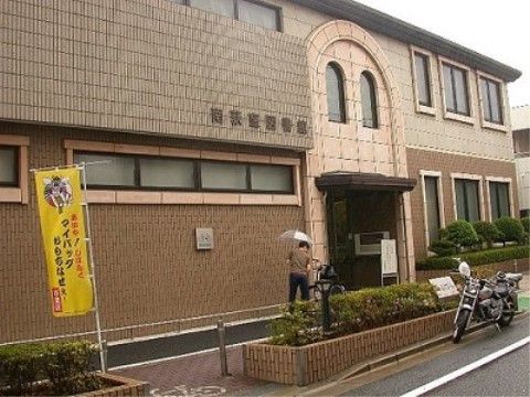 外壁が茶色をベースとしたツートンカラーになっている。建物に隣接した場所に綺麗に手入れされた植え込みがある。