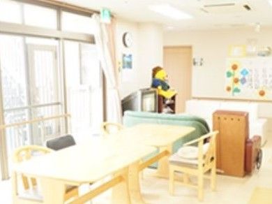 長机と椅子、キッチンがある小さなリビング。ソファが置いてあるリラックススペースもある