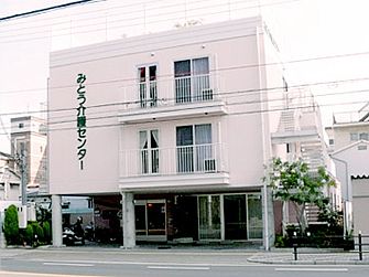 ３階建ての建物の左側に「みとう介護センター」と書かれている。１階部分には駐車スペースもあり。