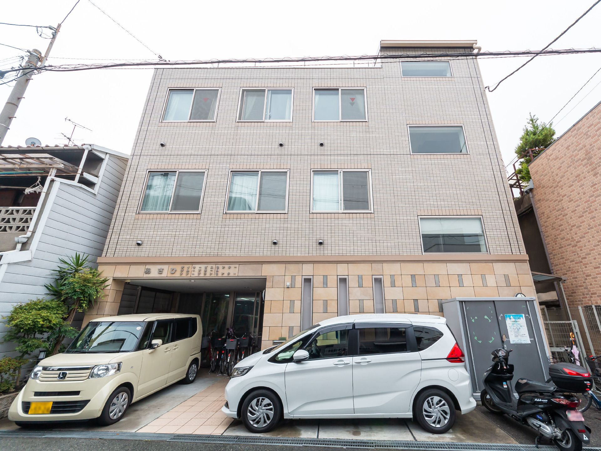 三階建ての建物の前に止まっている２台の車