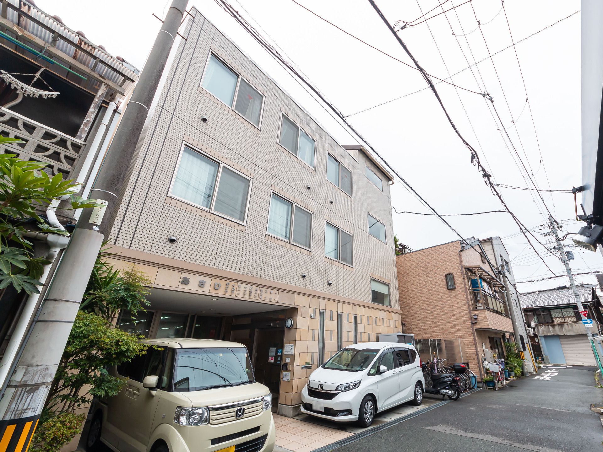 高齢者の方にタオルをかけてマッサージしているスタッフと振り返りながら会話する女性の様子