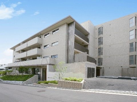 介護施設の外観。4階建ての建物の入口に花壇が設けられている。