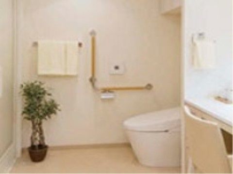 横に洗面台を備えたトイレスペースである。ゆったりとご利用いただける空間を設け、角には観葉植物を飾っている。
