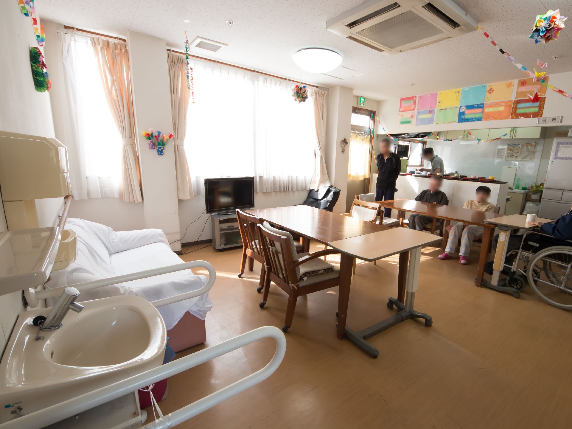 左手前に洗面台があり、流しの両側に手すりが取りつけられている。洗面台の奥には白いソファが置かれている。