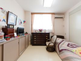 寝具付きのベッドが置かれた部屋にはタンスなどの収納スペースも多く、エアコンやテレビもある。