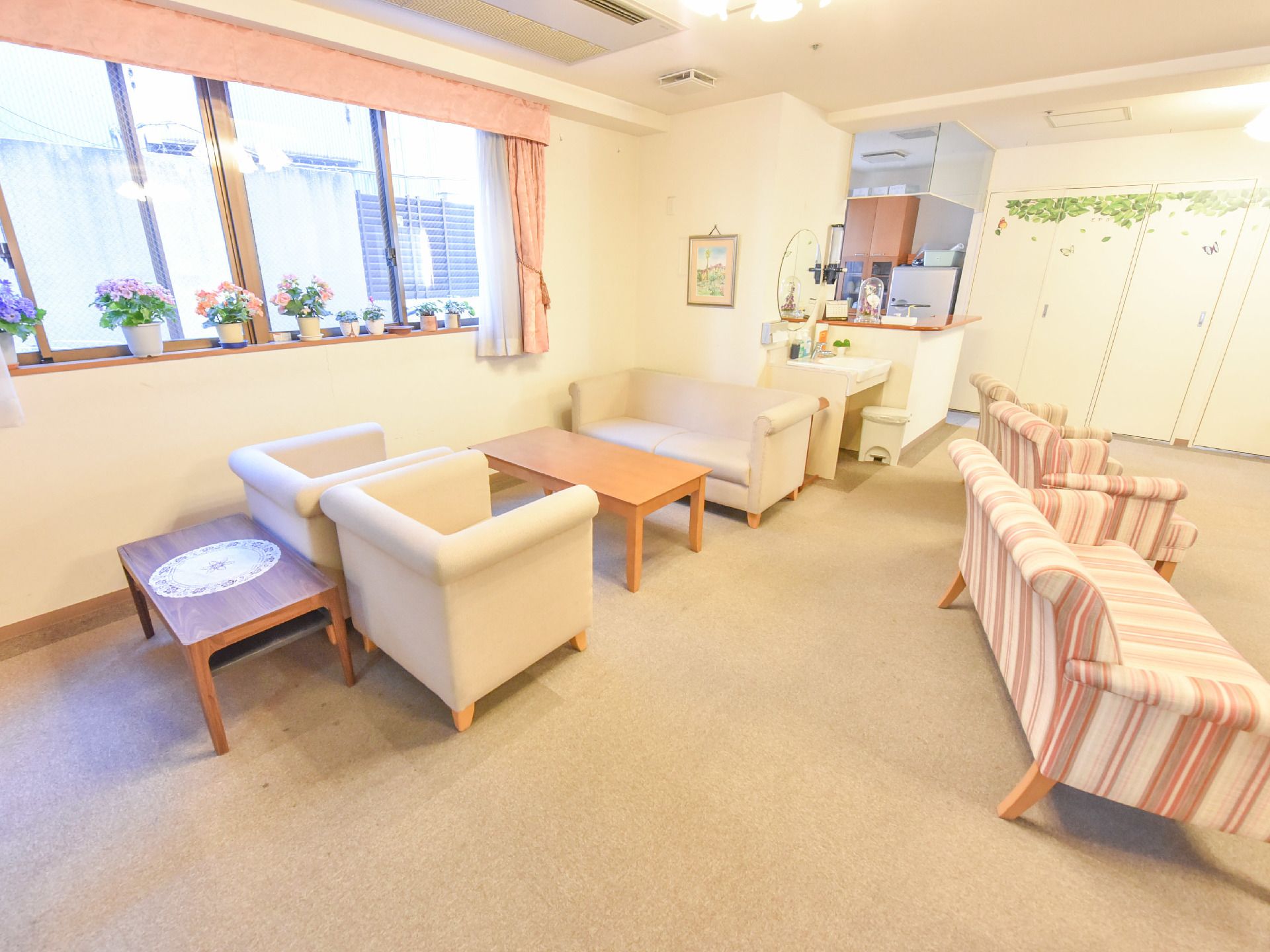 横一面には窓があり、すぐ下部にはテーブルとソファが置かれている。ソファの後ろにもテーブルがあり、壁には絵が飾ってある。