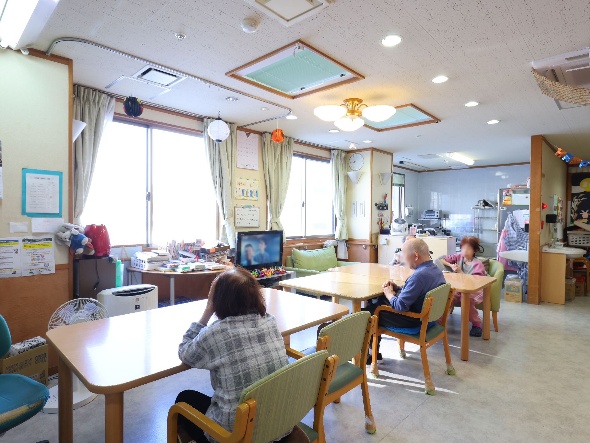 テーブル、椅子が置かれ、窓から陽光が入っている部屋