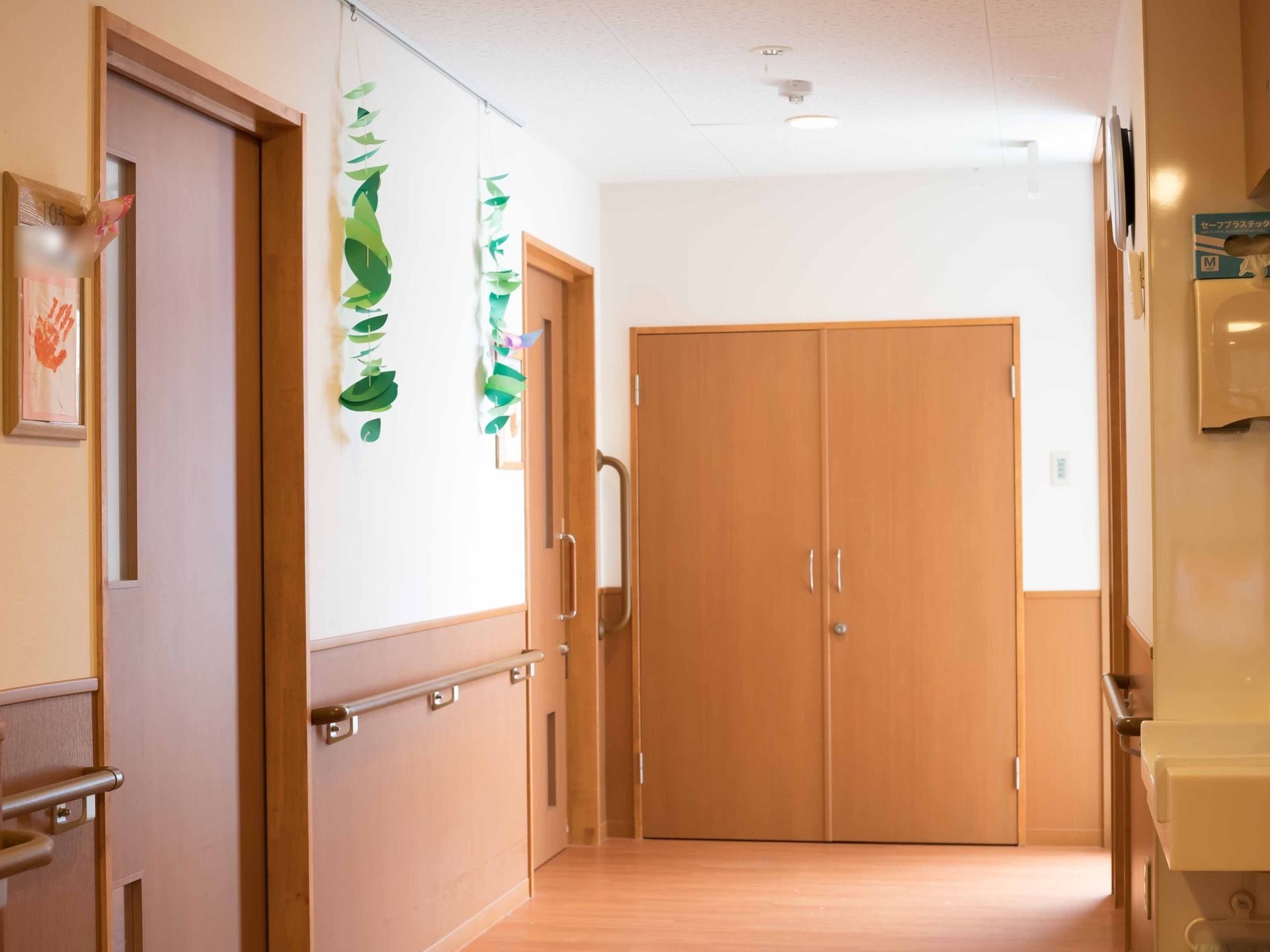 施設内の壁は白と明るいウッド調で統一し、床やドアもウッド調で色合いを統一している。廊下には手すりがついている。