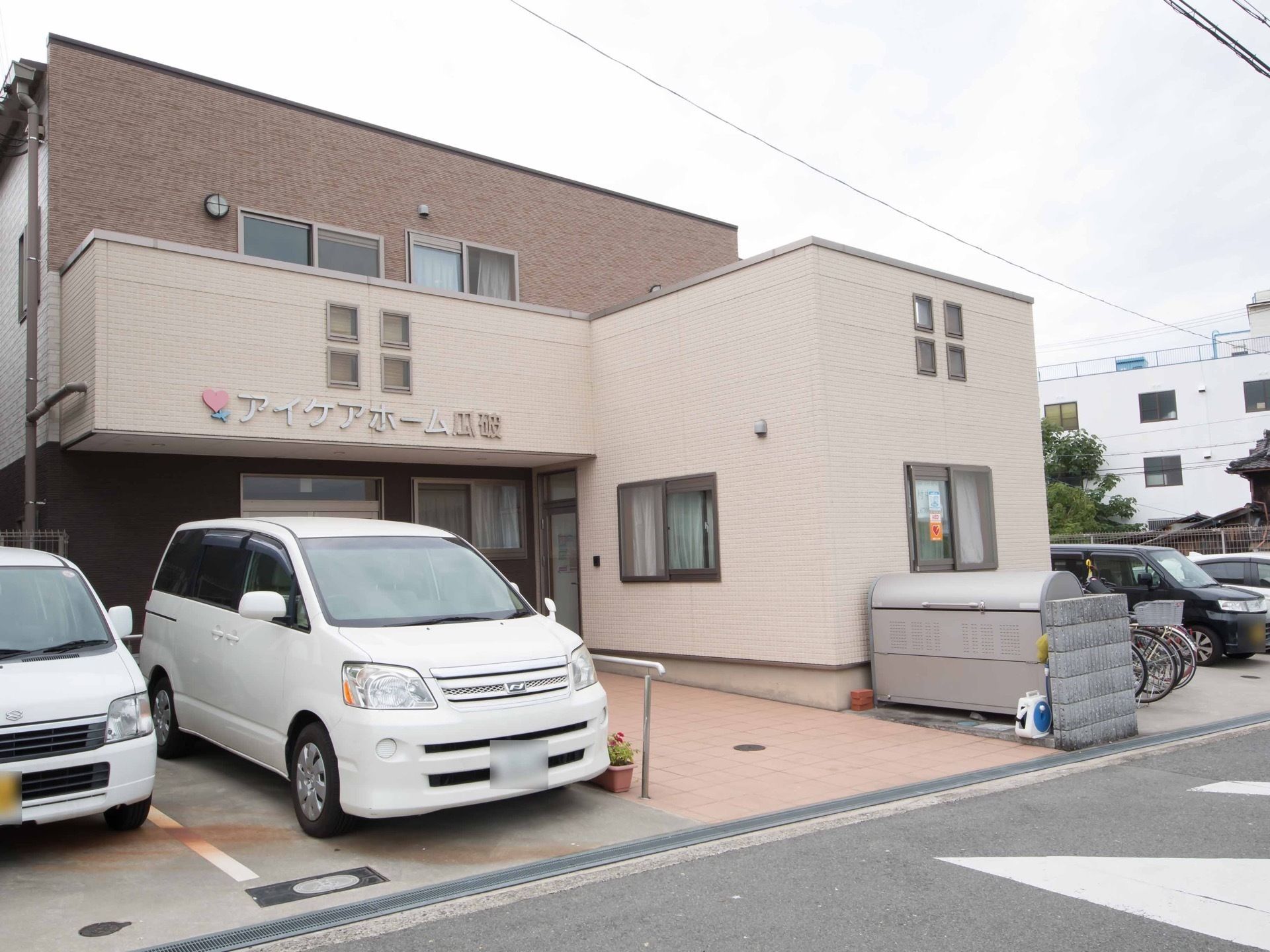 施設の前に駐車場とゴミ捨てスペースがある。玄関への通路には手すりが設置してあり、転倒防止柵が施されている。