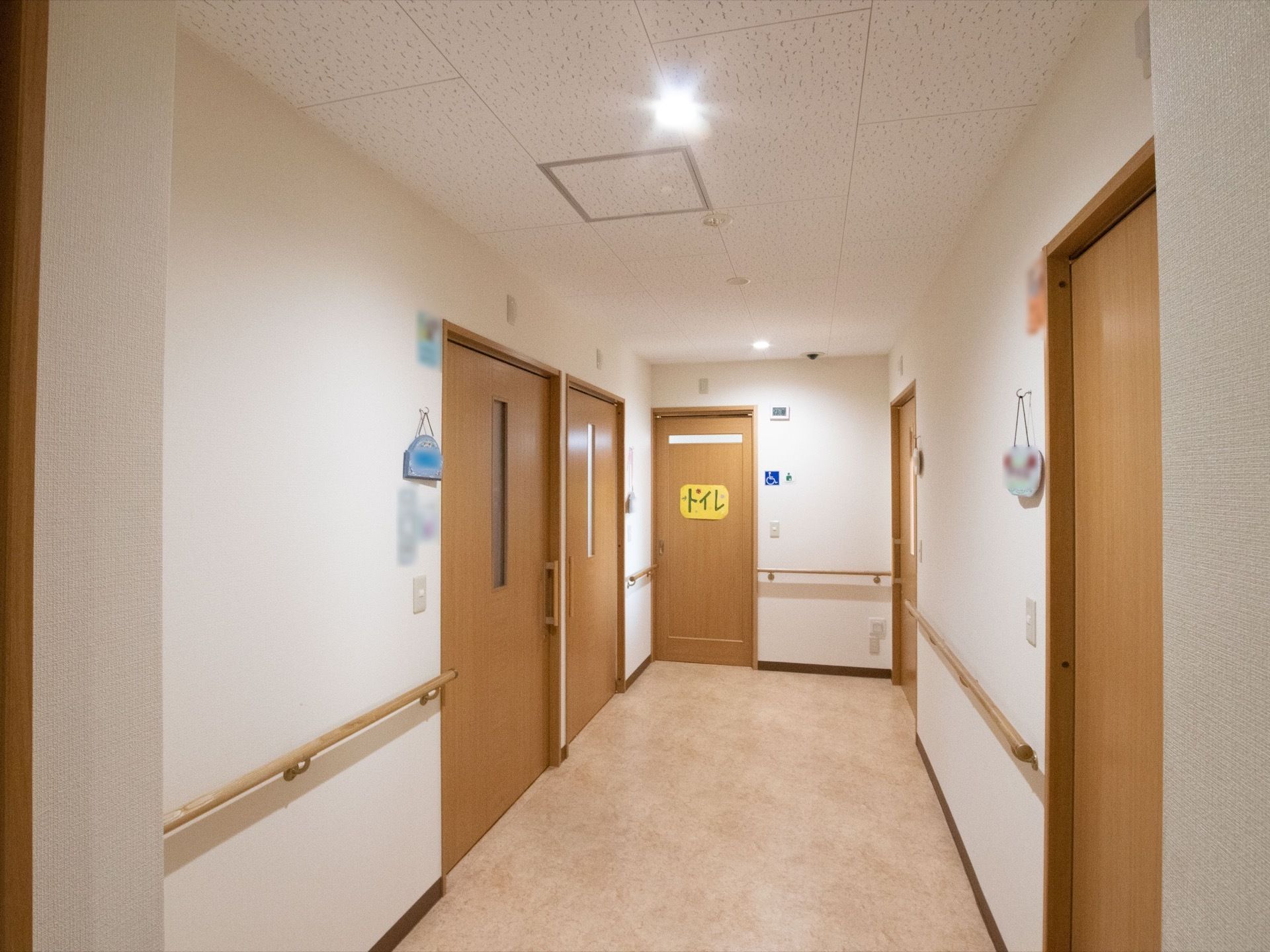 手すりが両側に設置されている。突き当りにトイレがあり、大きくトイレと書かれた紙がドアに貼られている。