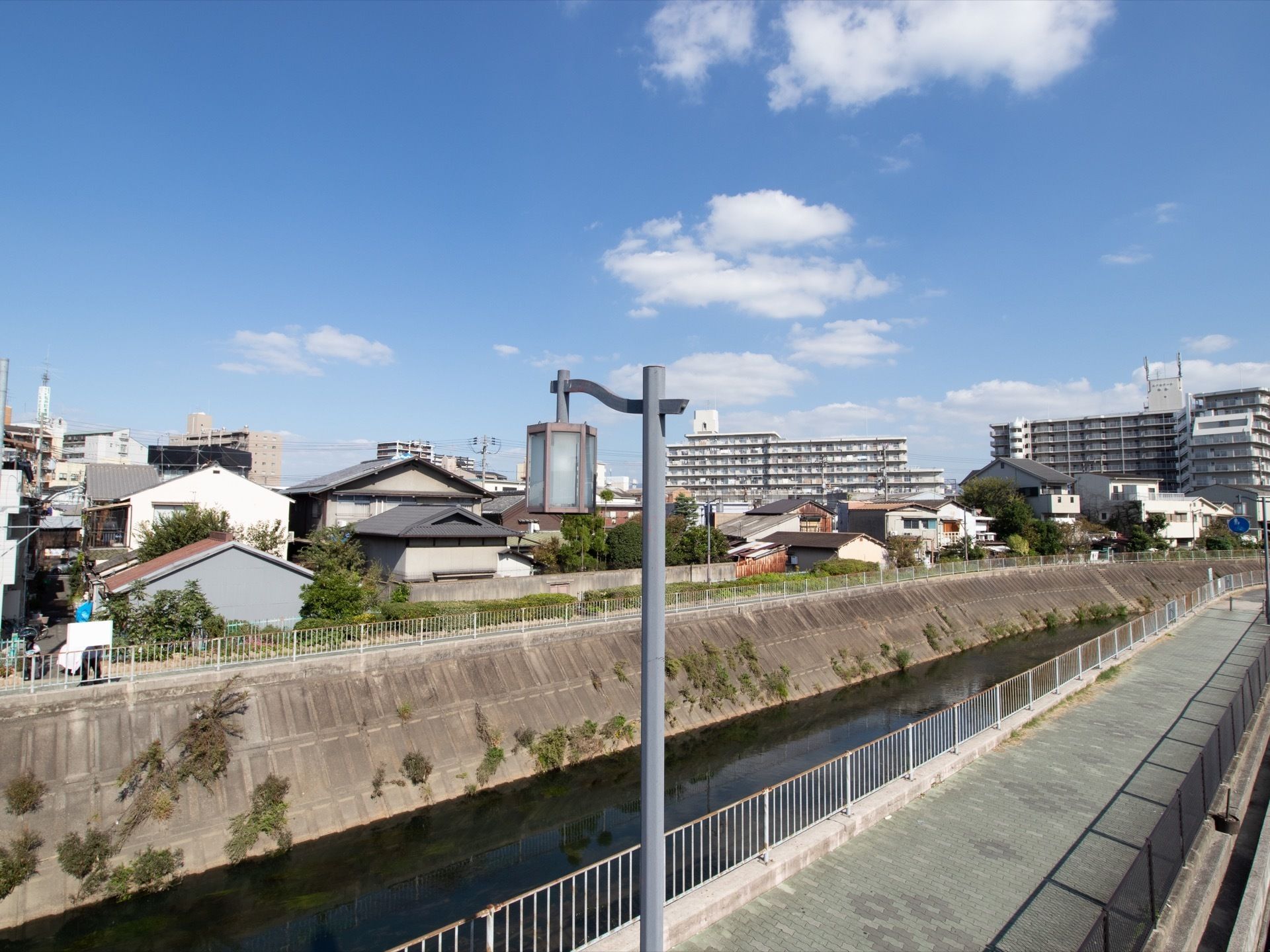 目の前には川があり、広々とした散歩道がある。近くには視界を遮る大きな建物はなく、住宅街が広がっている。