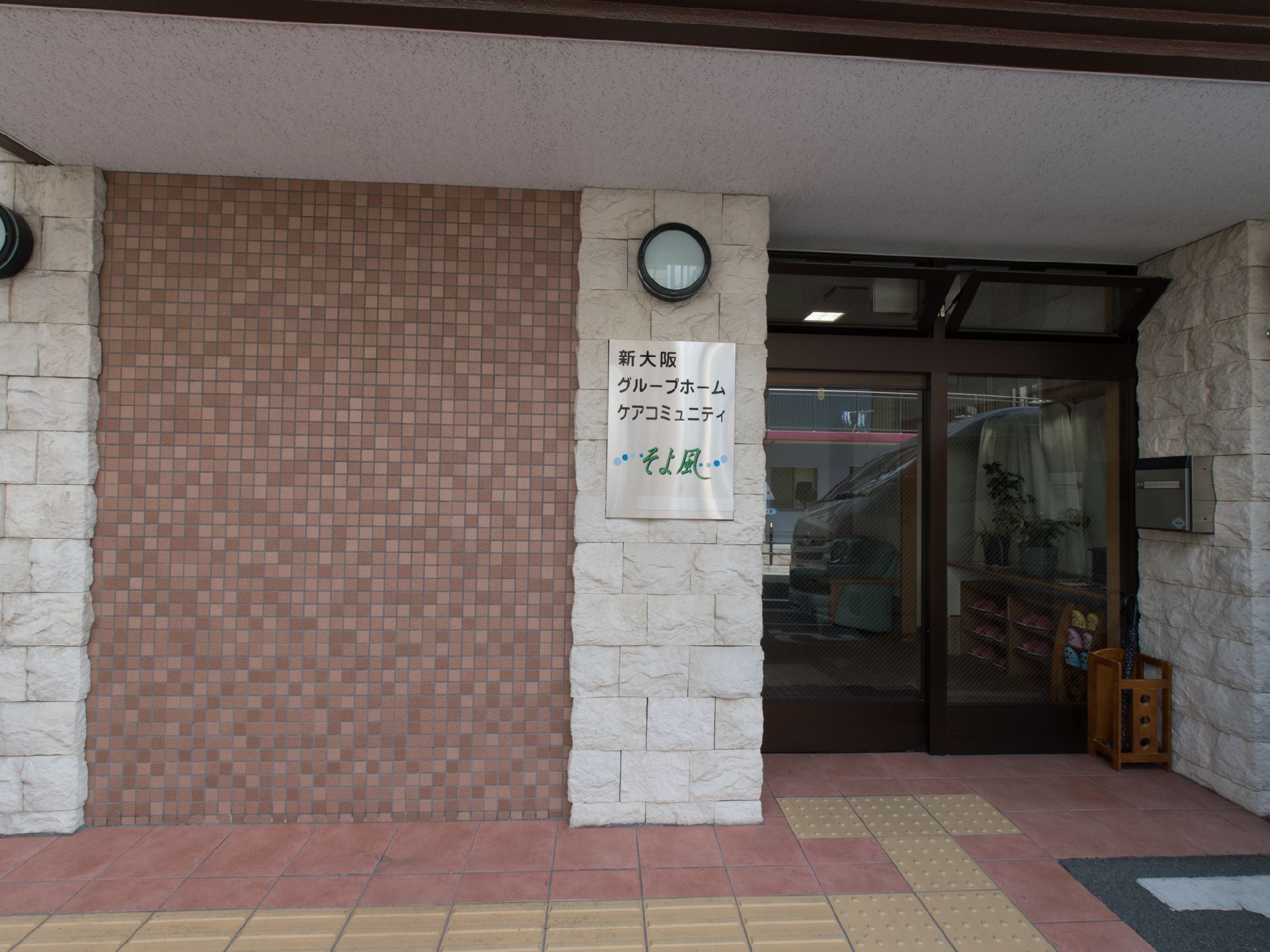 施設の外壁は白のレンガ状の柱と茶色のタイル壁で構成されている。茶色のタイル壁には青の玉と緑の文字で施設名のロゴが大きく取り付けられている。