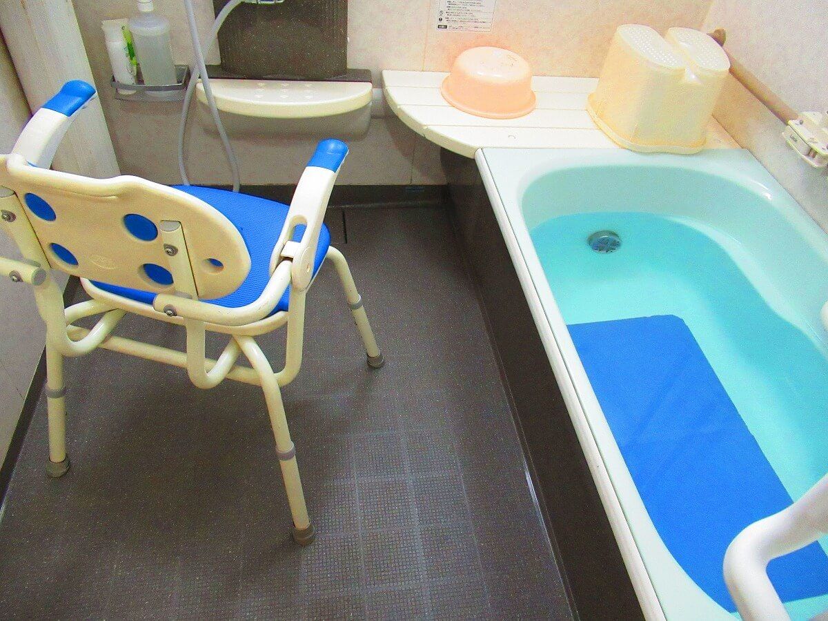 一般家庭と変わらないサイズの浴槽。浴室の壁にはシャワーや手すりが設置され、シャワーチェアもある。