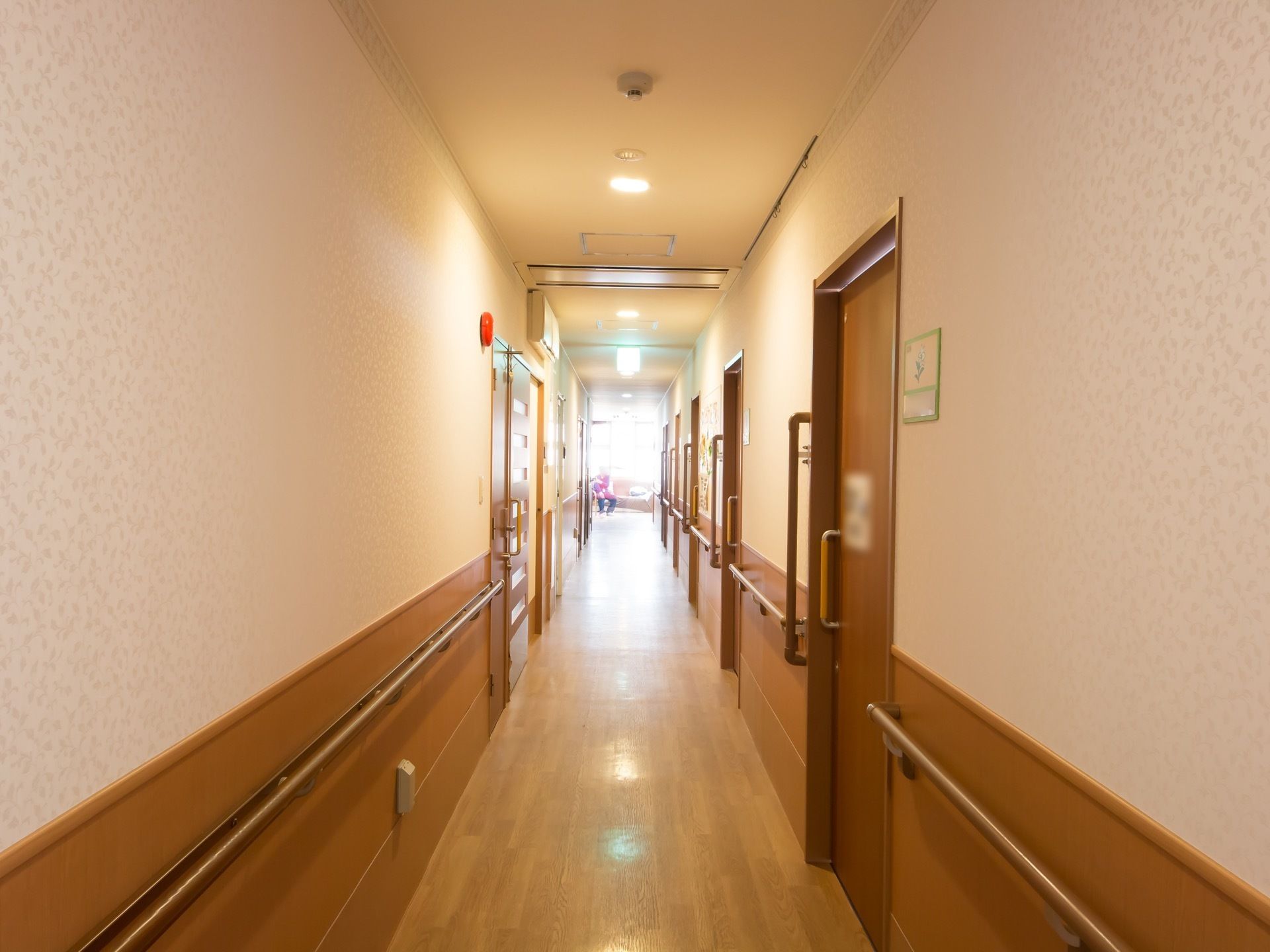 清潔感とあたたかみのある白と木目調で作られた通路。左右に手すりがあり、ドアは使いやすいよう引き戸になっている。