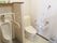 エル字型の手すりや呼び出しボタンが設置された洋式トイレが右手にあり、男性用の小便器が左側にある。