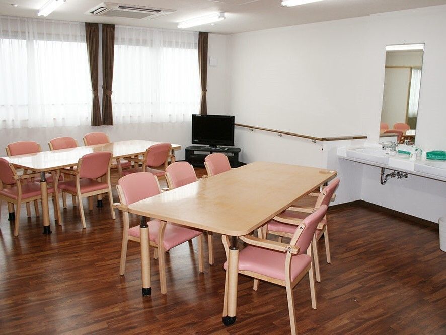 5脚ずつ椅子がセットされたテーブルセットが二つ置かれた食堂には大きな窓がたくさんつき、テレビや洗面所もある。