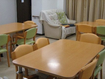 複数のダイニングテーブルが置かれたリビングダイニング。奥の壁にはソファが設置されている。