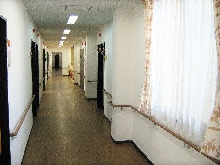 大きな窓が付いたまっすぐな廊下。入居者がわかりやすいよう壁と手すりの色が異なる。