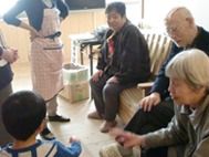 子供を囲んで楽しそうにしている入居者数名の姿。