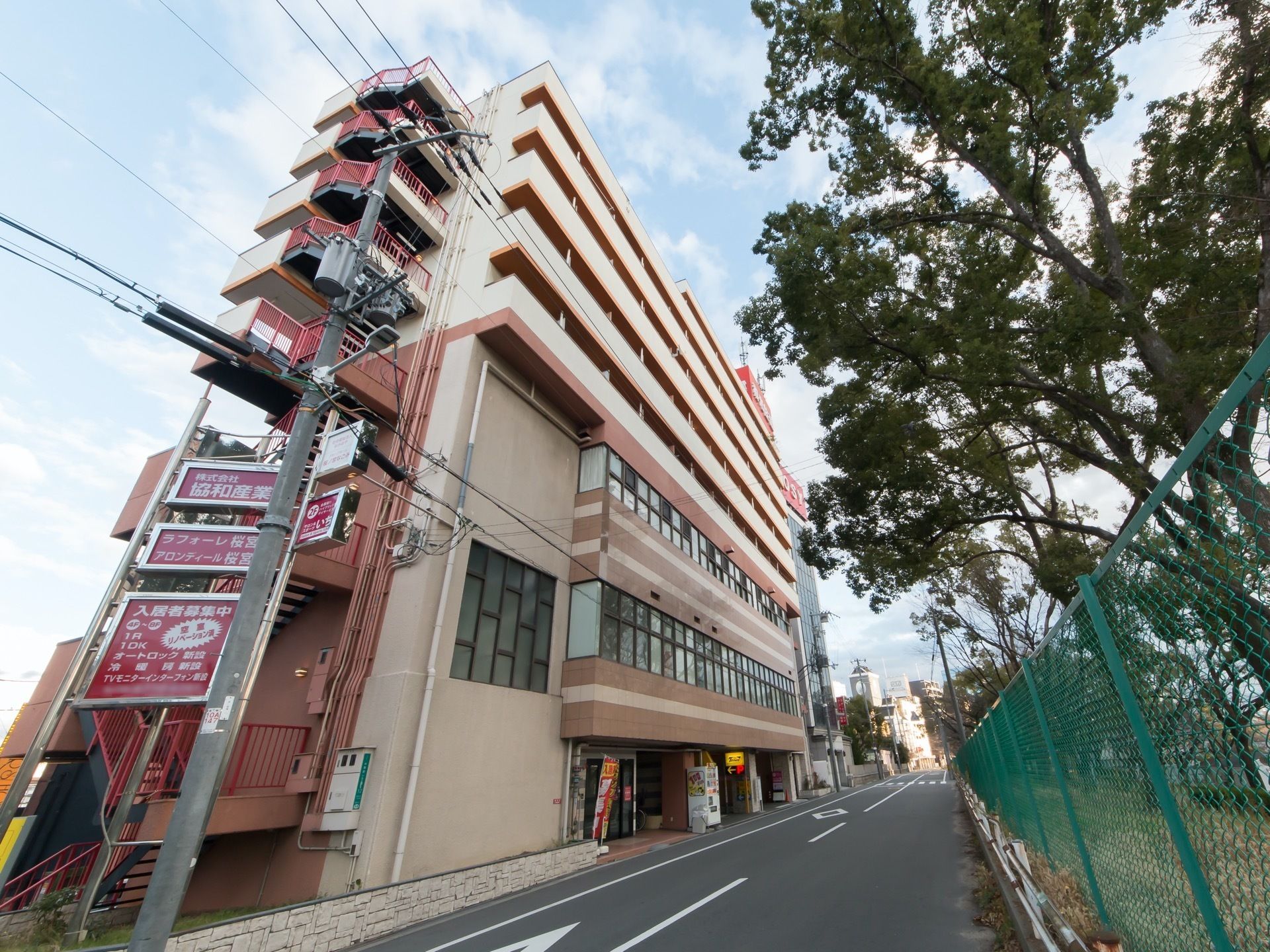 ８階建ての大きな建物で、横には非常階段が設置されている。駐車場前には、１台の自動販売機が設置されている。