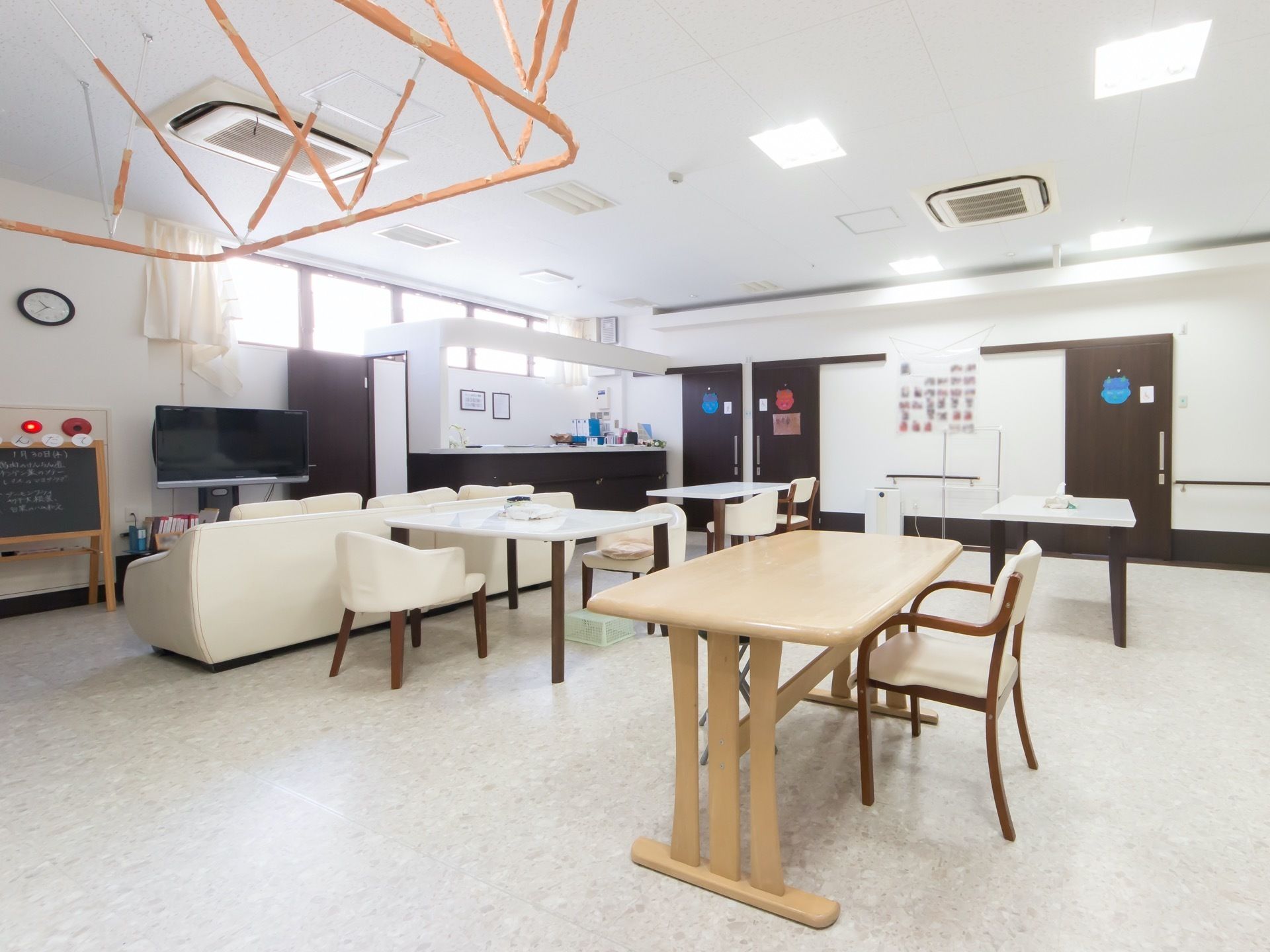 居室前に設けられている開放的なリビングダイニングである。複数のテーブルと椅子が、セッティングされている。