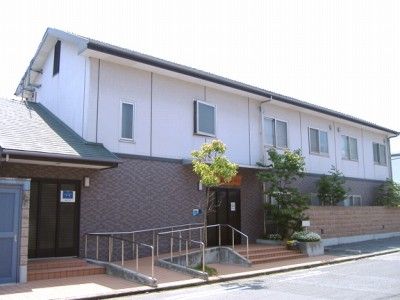 白と茶色を基調とした外観の二階建ての建物