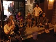 夏の夜にホームの玄関先で話をしているスタッフと入居者の様子。