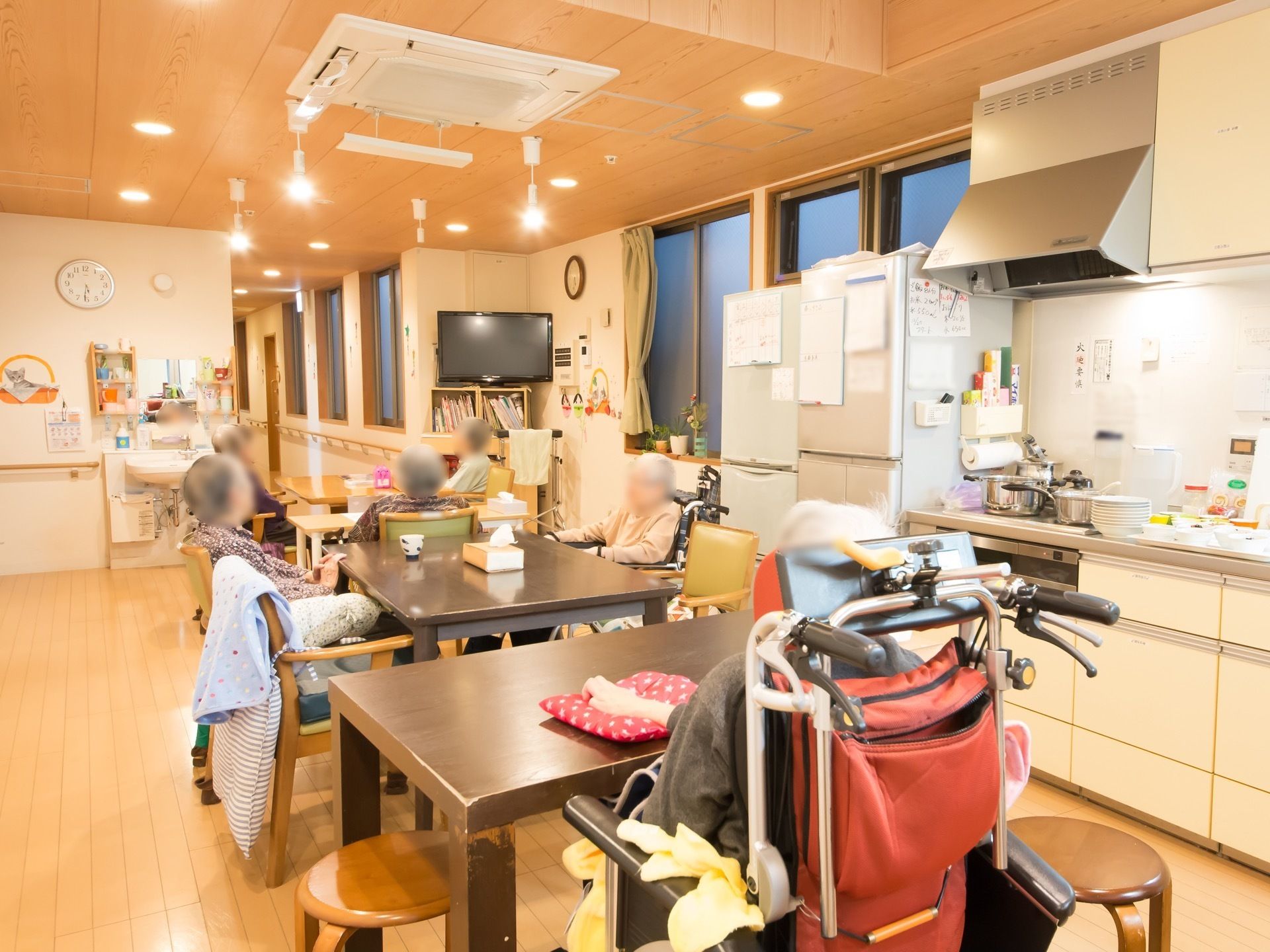 食堂にはテーブルと椅子が並べられている。椅子には入居者様が座っている。壁には手すりが取りつけられている。