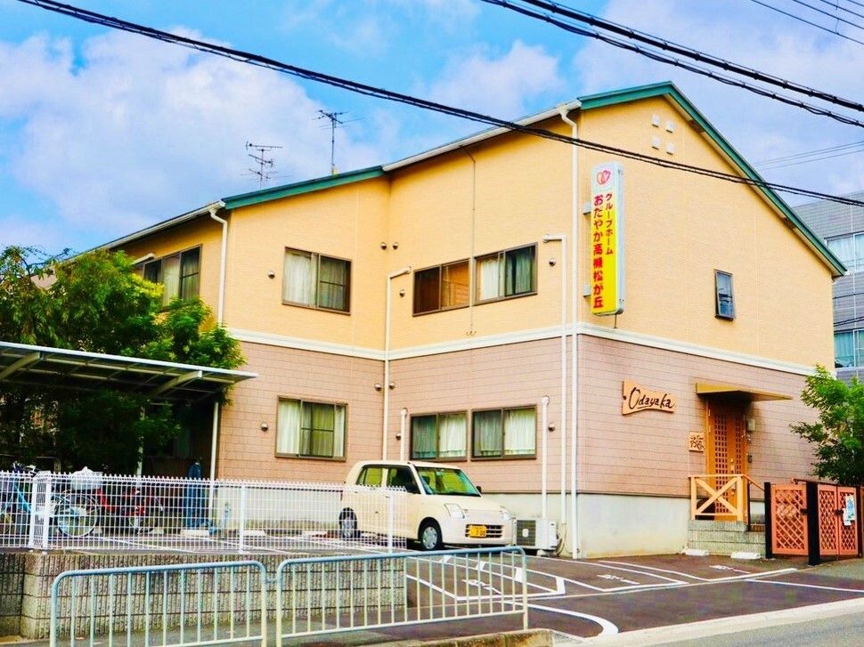 施設は大きな通りの曲がり角に建てられており、２階建てである。施設の前には歩道があり、歩道には低いフェンスが設置されている。