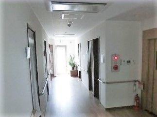 両側に手すりが付いた廊下の様子。エレベーターホールが右側にある様子