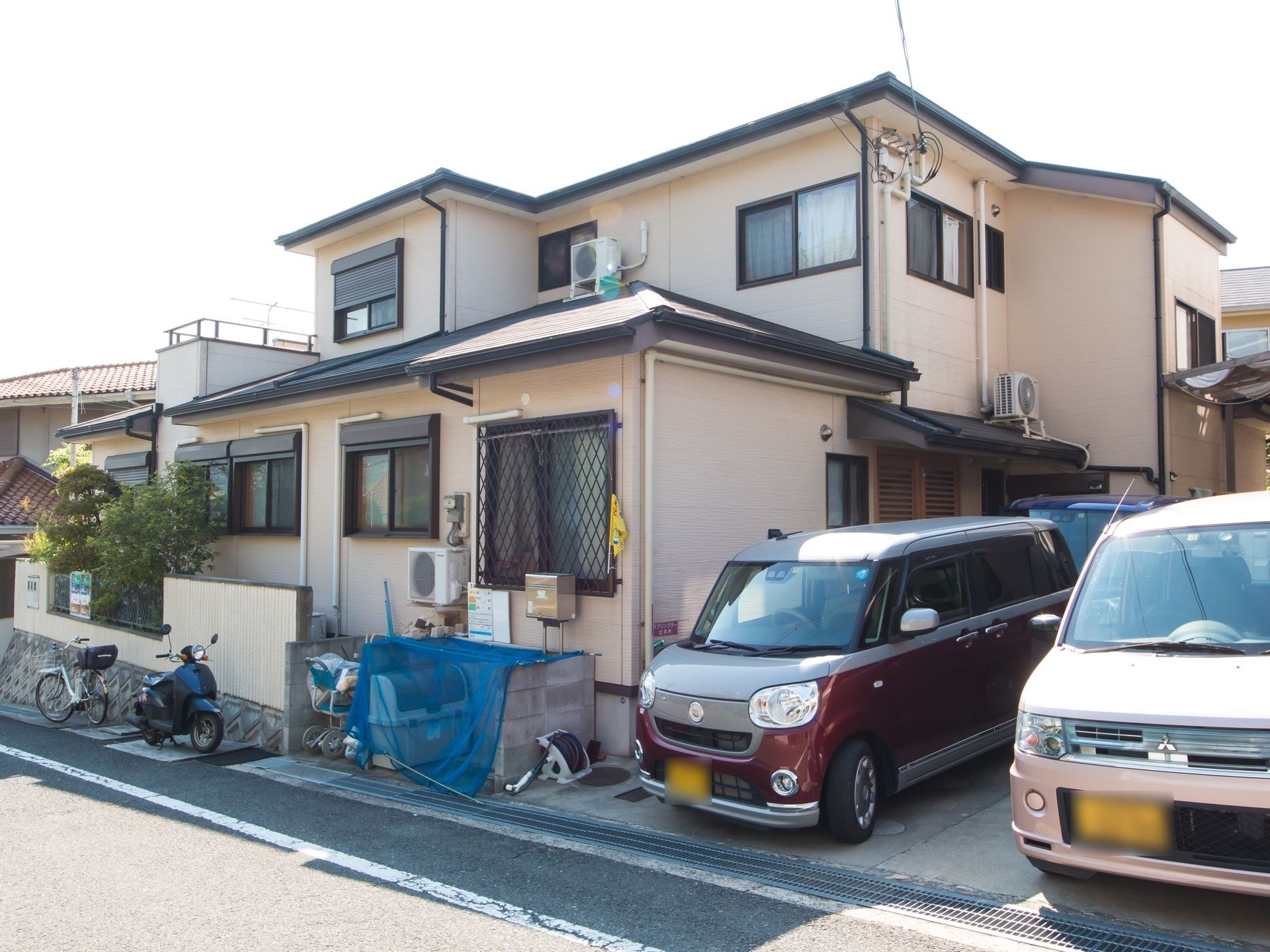 建物の周囲に、車が３台停まっているほか、バイクや自転車も停められている。また、ゴミ置き場には、ゴミかごが置かれ、上にネットがかかっている。