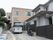 施設は住宅街に位置し、隣の建物は２階建ての一般住居である。施設の建物は外壁が明るいベージュ系の２階建てで、外壁面に施設名が表示されている。