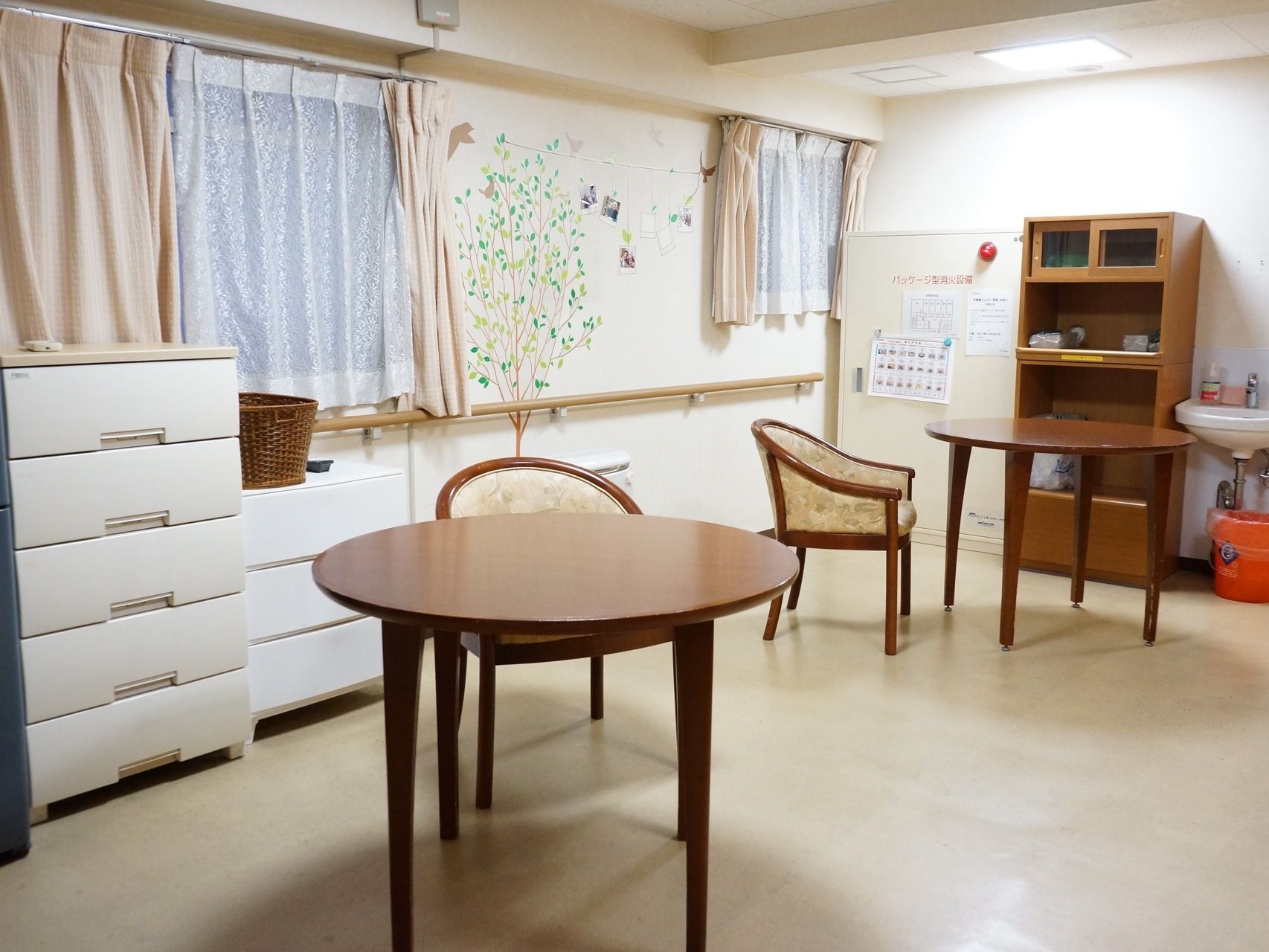 リビングには手洗い場や消火設備なども備えつけられている。窓側の壁は可愛らしい木のイラストで装飾され、アットホームな雰囲気を作っている。