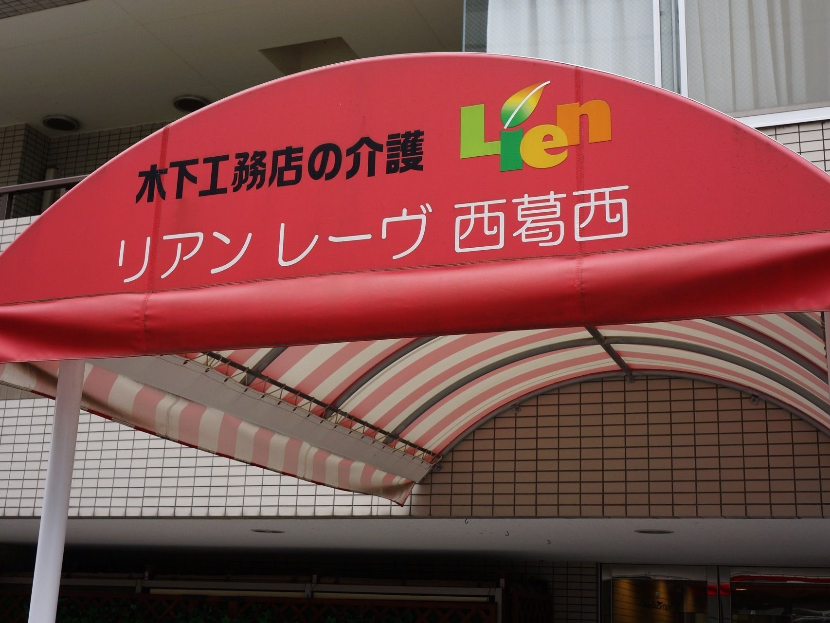 玄関前の屋根は鮮やかな赤で、前方の側面は赤地にカラフルなロゴと施設名が書かれているが、後方は赤と白のストライプである。