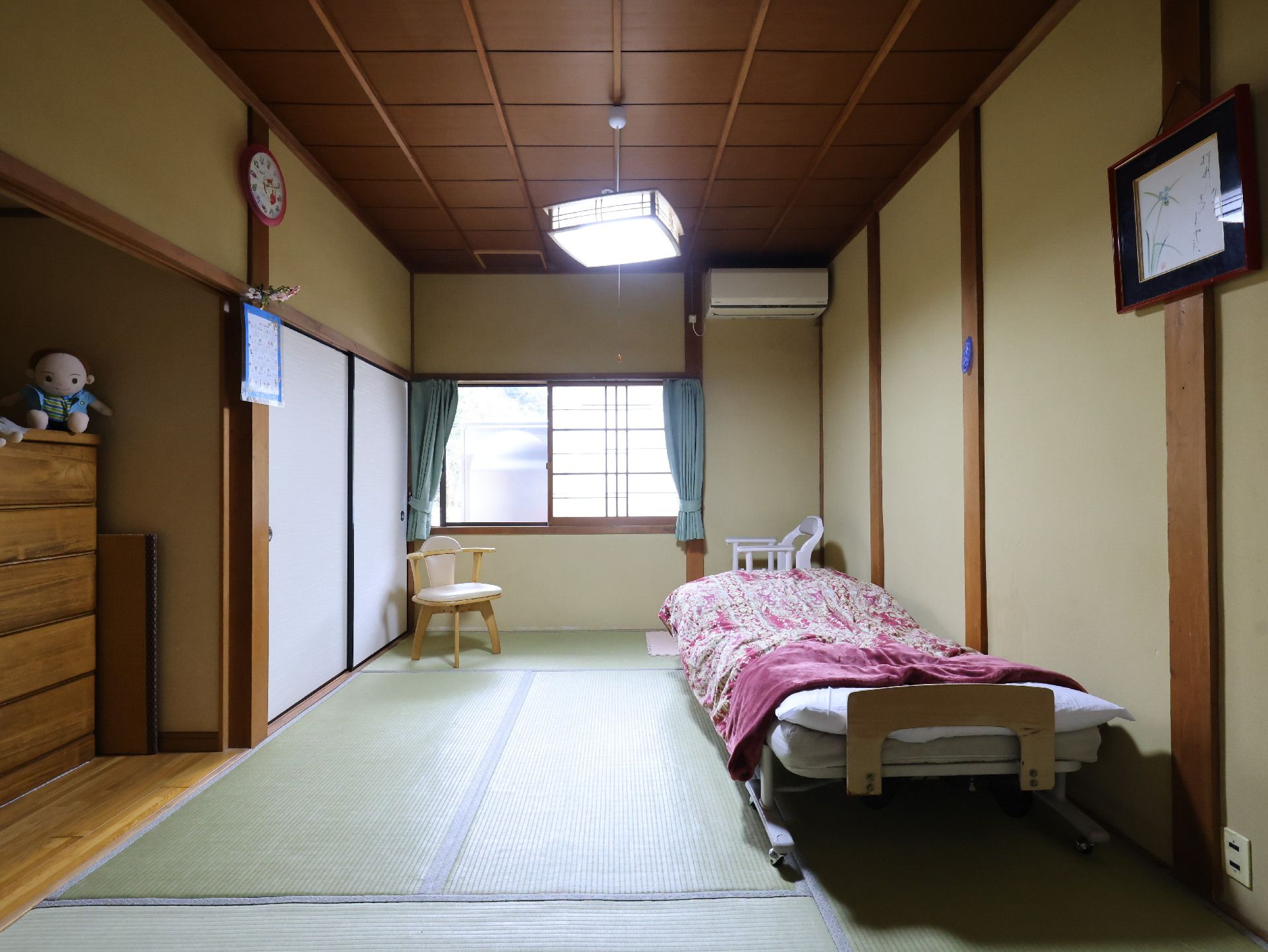 窓から日差しが差し込み、介護ベッドが置かれている居室