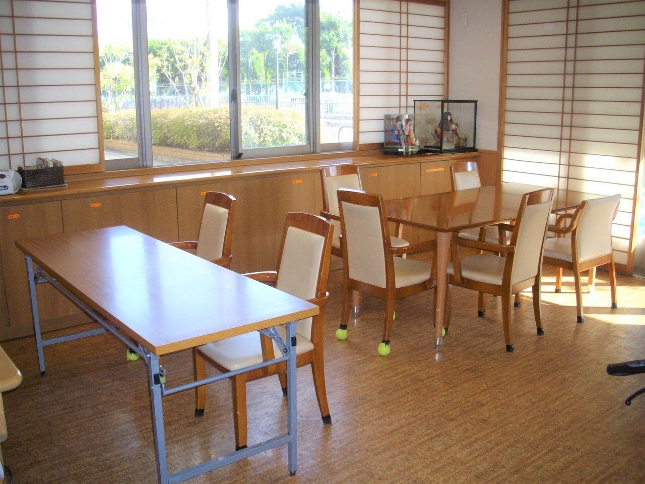 木製のダイニングテーブルが複数置かれたリビングダイニングには日本人形なども飾られている。