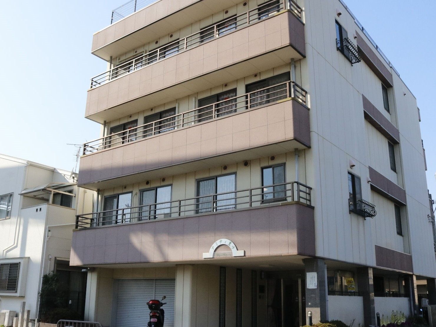 各フロアにベランダが付いたベージュ系の外観の４階建ての建物は日当たりのいい場所に建っている。