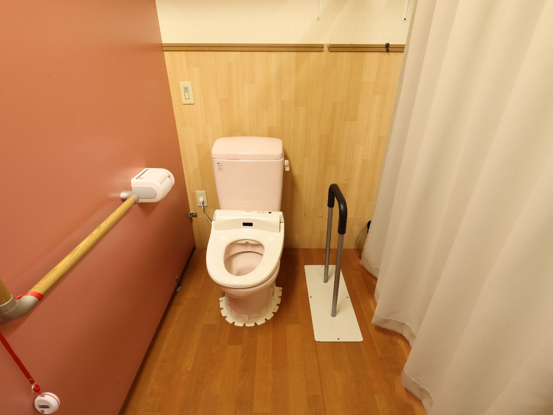 バリアフリー完備で、壁に手すりが付き、床の段差が解消されているトイレ