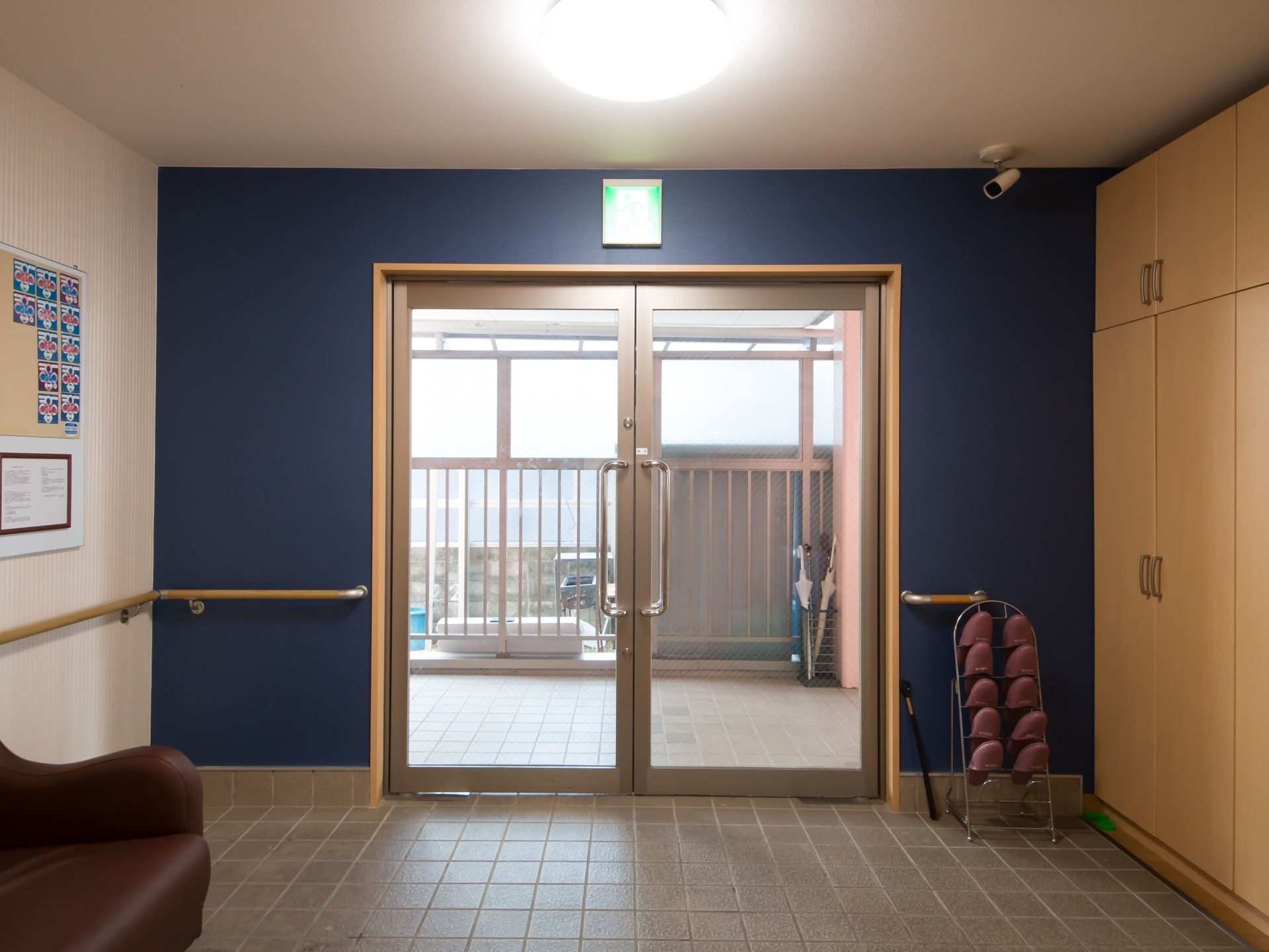 落ち着いた、ブルーの壁が印象的な玄関である。広々とした開き戸タイプの扉を完備。手すりも備えつけられている。