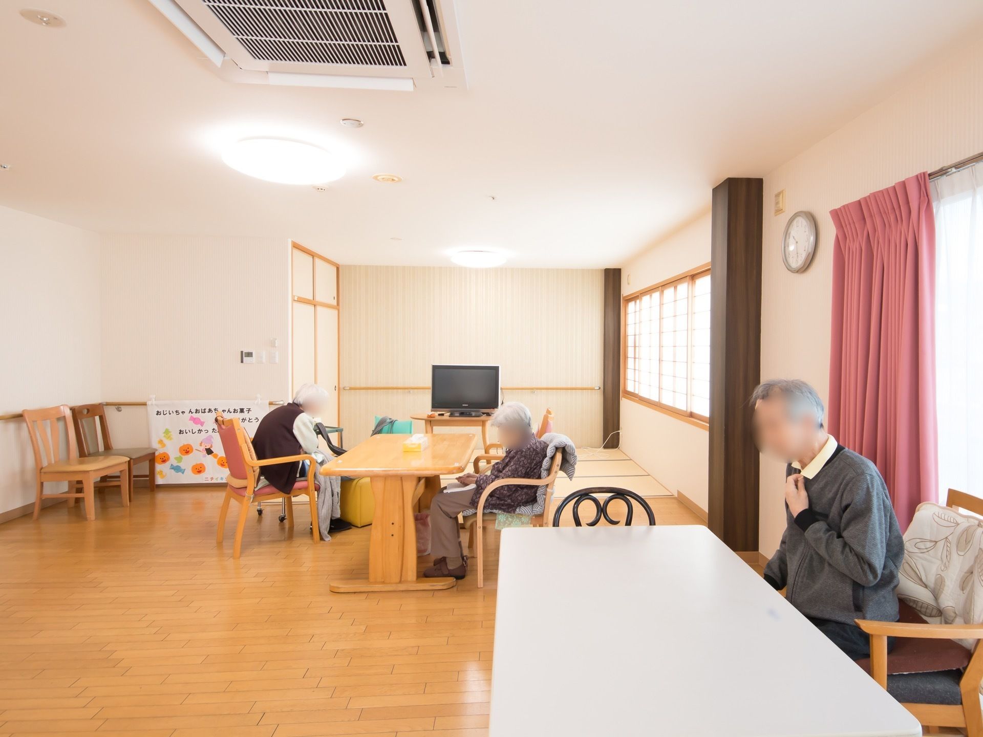 広々とした、共有スペースである。テーブルと椅子が備えつけられており、入居者様が思い思いの時間を過ごしている。