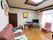 天井の照明器具の周りに模様が入っており、木枠がある。部屋の隅にテレビ台を置き、プレイヤーとテレビを設置している。