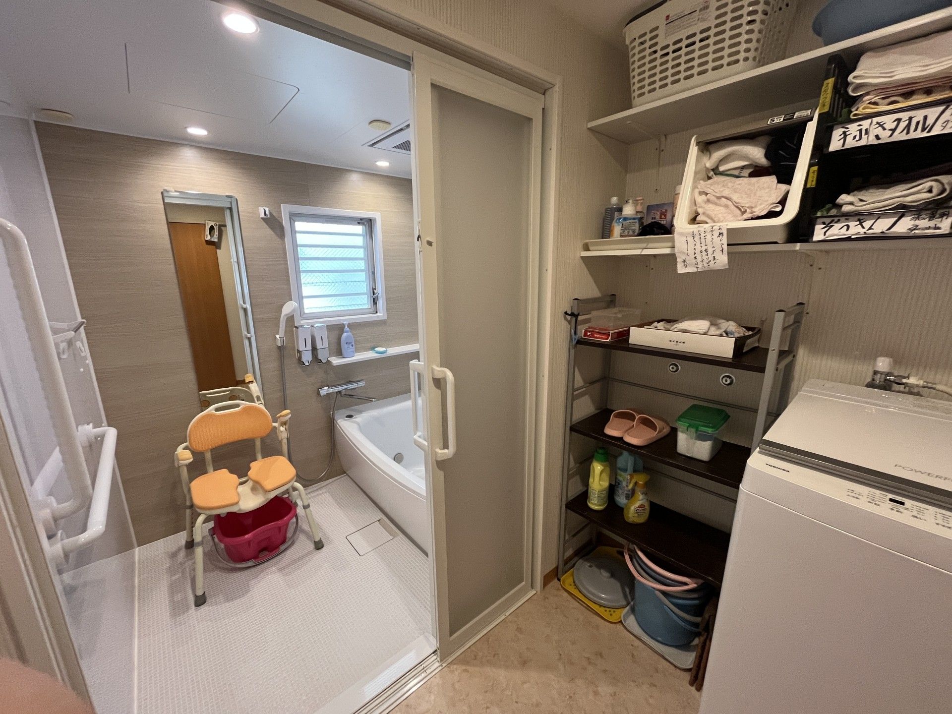 木陰にいる車椅子に乗った高齢男性と隣に寄り添う女性ヘルパー