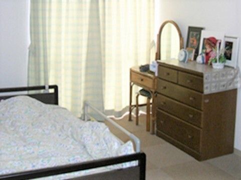 鏡台やタンス、寝具付きのベッドなどが置かれた部屋には、大きな窓があり、カーテンが付けられている。