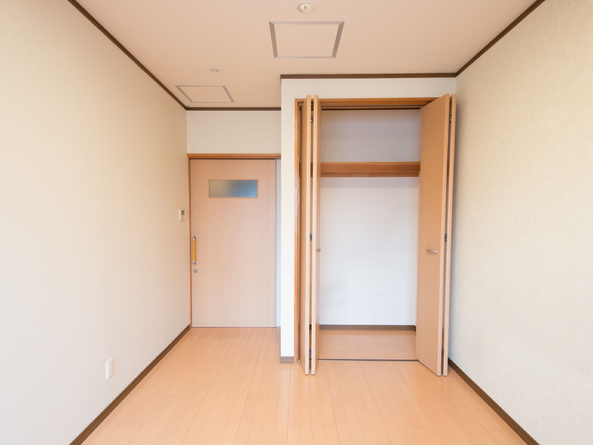 左奥は四角い窓のついた入口扉があり、引き戸になっている。入口横は折れ戸式の収納スペースが用意されている。