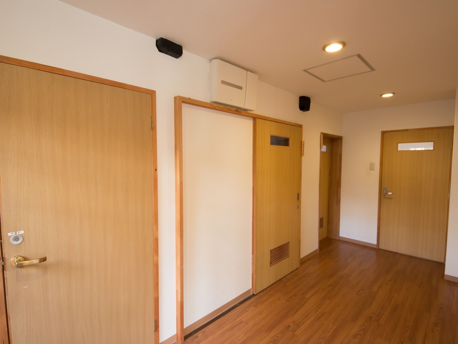 居室の扉は木目調になっている。フローリング敷の廊下は幅を広くとっている。壁は白を採用、天井には埋め込み型の照明が設置されている。