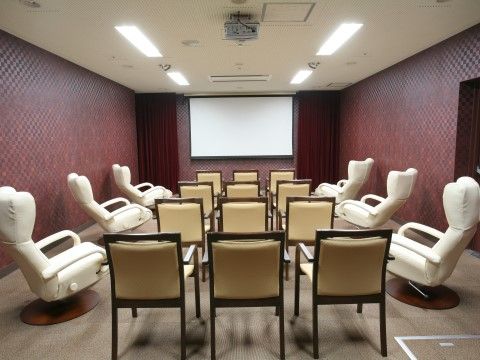 奥にスクリーンが設置され、その前にソファーや椅子が並べられているシアタールーム