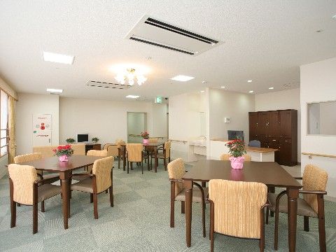 ４人掛けのダイニングテーブルとひじ掛け付きの椅子が、複数セット置かれている。床にはグレーのカーペットが敷かれている。